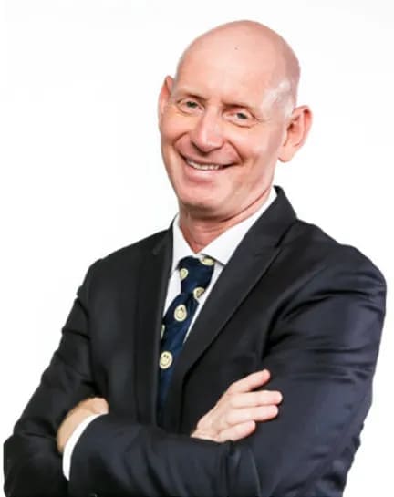 A bald man in a suit and tie smiling, radiating confidence and professionalism.